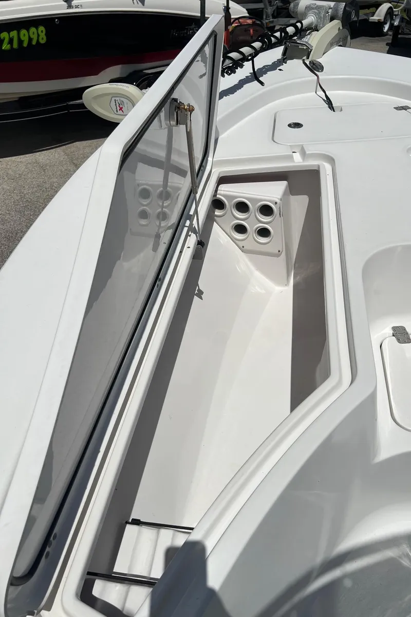 Slide: The Image of 2015 Sportsman Masters 247 Bay Boat storage compartment with open lid and rod holders. - 30
