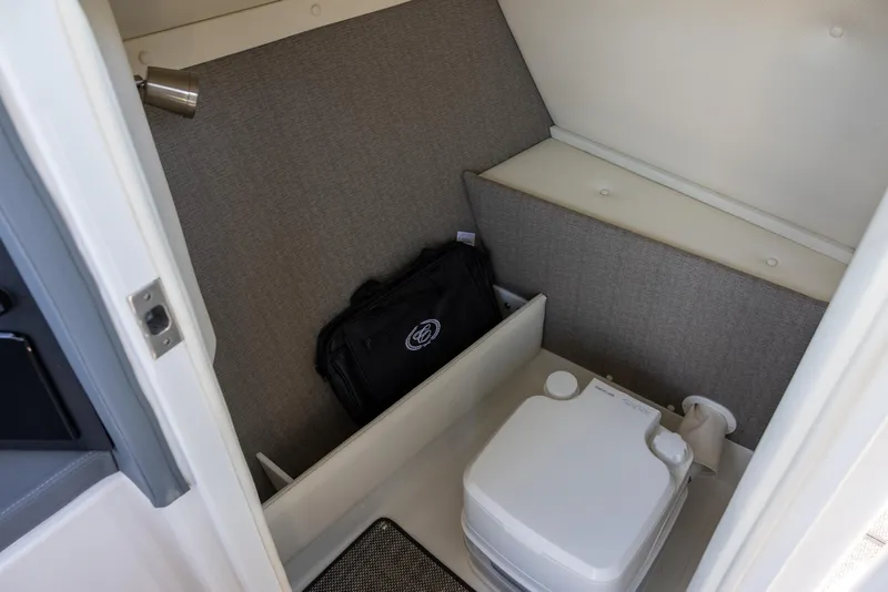 Slide: The Image of 2019 Cobalt 25SC boat interior with compact toilet and storage area. - 13