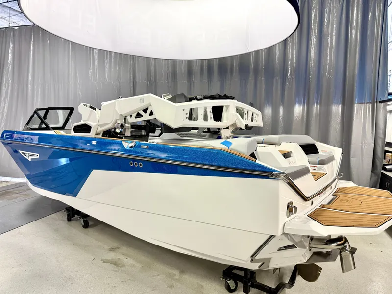 Slide: The Image of 2025 Nautique Super Air Nautique S23 boat in showroom, featuring sleek blue and white design. - 16