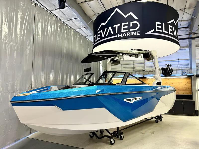 Slide: The Image of 2025 Nautique Super Air Nautique S23 boat in showroom, blue and white design, Elevated Marine display. - 17