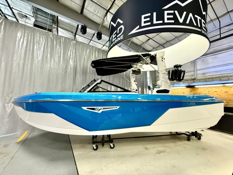 Slide: The Image of 2025 Nautique Super Air Nautique S23 boat in showroom, blue and white design. - 18