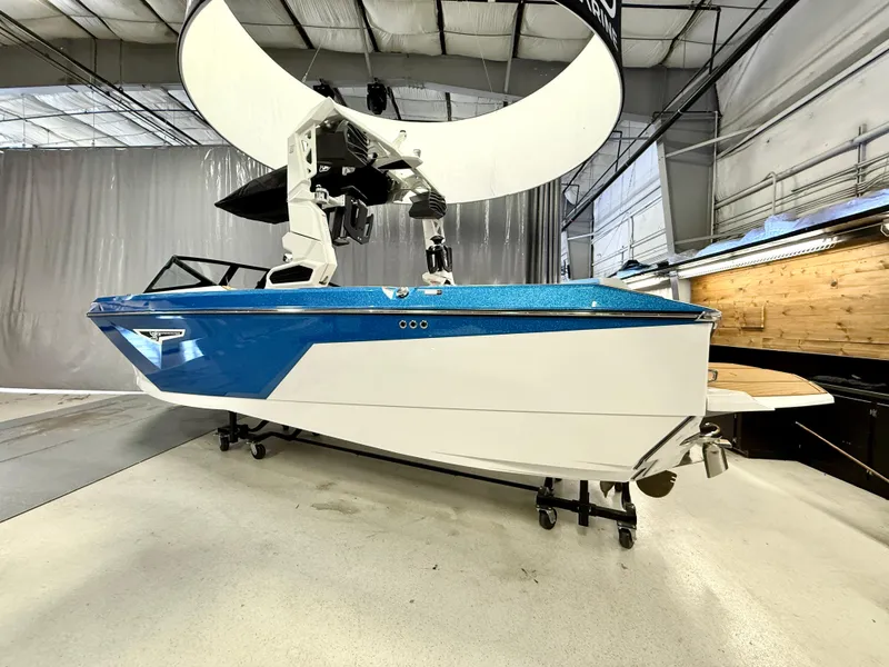 Slide: The Image of 2025 Nautique Super Air Nautique S23 boat in showroom, blue and white design. - 2