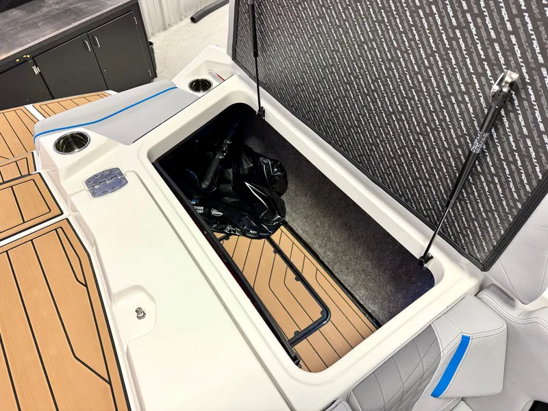 Slide: The Image of 2025 Nautique Super Air Nautique S23 storage compartment with open lid and teak flooring. - 34