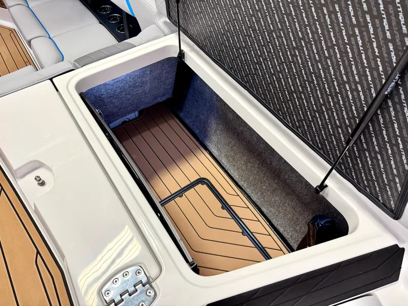 Slide: The Image of 2025 Nautique Super Air Nautique S23 storage compartment with cushioned seating and teak flooring. - 36