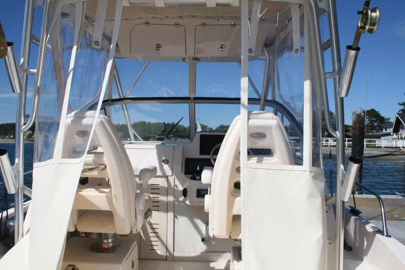 Slide: The Image of 2021 Grady-White 232 Gulfstream boat interior with helm and seating, docked by the water. - 5