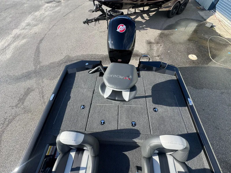 Slide: The Image of 2026 Vexus AVX1980 boat interior with seating and motor, parked on pavement. - 11