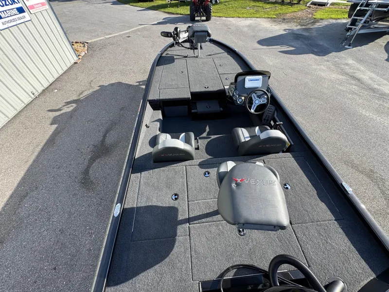 Slide: The Image of 2026 Vexus AVX1980 boat interior with seating and steering console, parked outdoors. - 12
