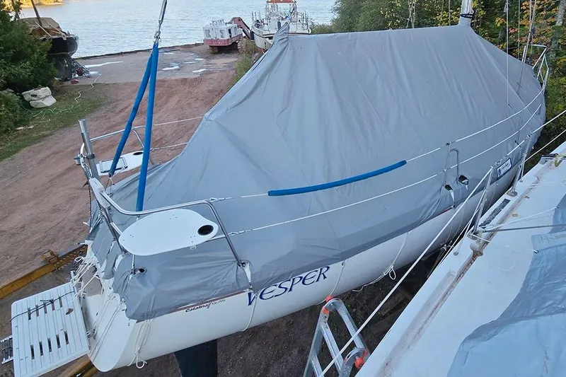 Slide: The Image of 1988 Catalina 34 mkI sailboat covered, docked near a serene waterfront. - 10