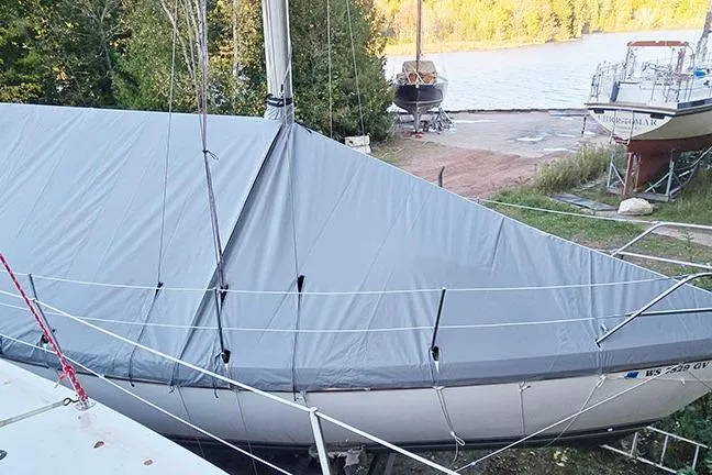 Slide: The Image of 1988 Catalina 34 mkI sailboat covered, docked near a serene lake with trees. - 11