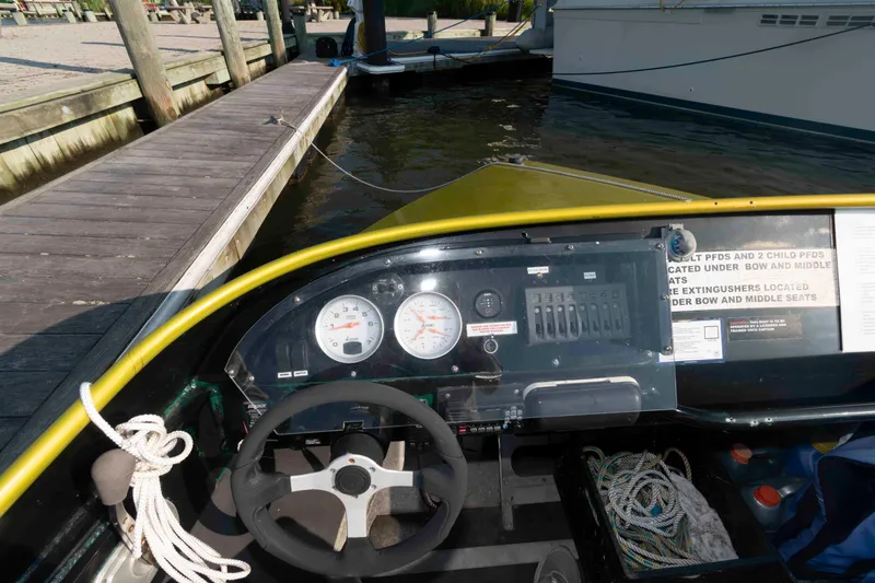 Slide: The Image of Cockpit view of a 2014 Custom Smokey Mountain Jet Boat docked by a wooden pier. - 6
