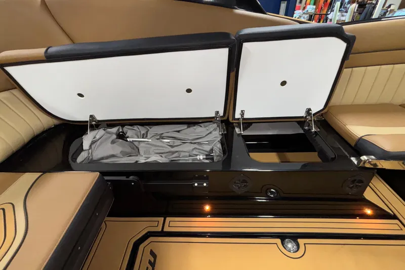 Slide: The Image of 2025 MB B52 25 Alpha boat interior storage compartment with open lids and beige seating. - 13