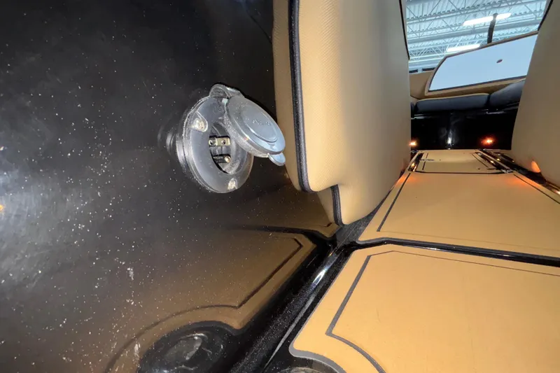 Slide: The Image of Interior view of 2025 MB B52 25 Alpha boat, featuring a power outlet and tan seating. - 25