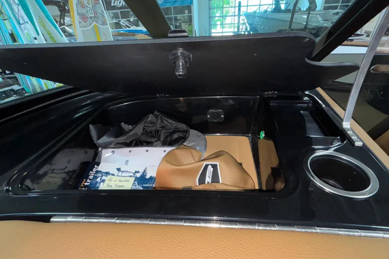 Slide: The Image of Open storage compartment in 2025 MB B52 25 Alpha boat, featuring cup holder and documents. - 5