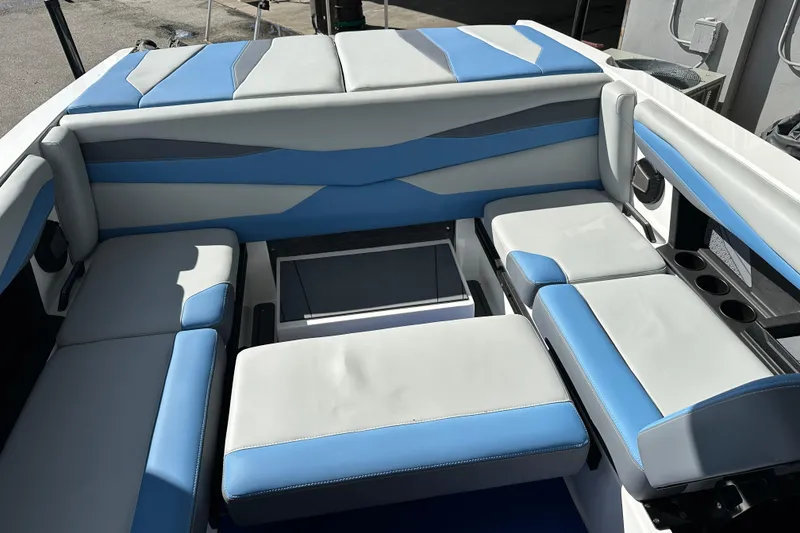 Slide: The Image of 2026 Axis A225 boat interior with blue and gray seating, featuring cup holders and storage. - 10
