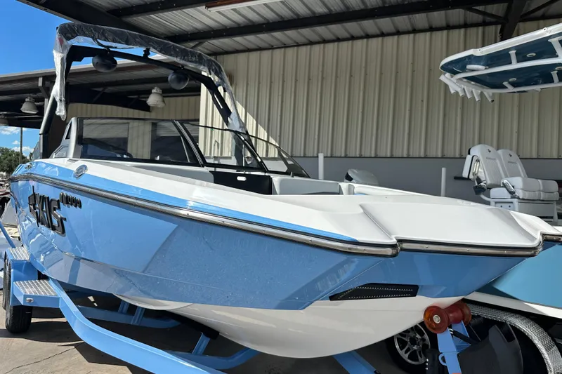 Slide: The Image of 2026 Axis A225 boat in showroom, blue and white exterior, under a metal roof. - 12