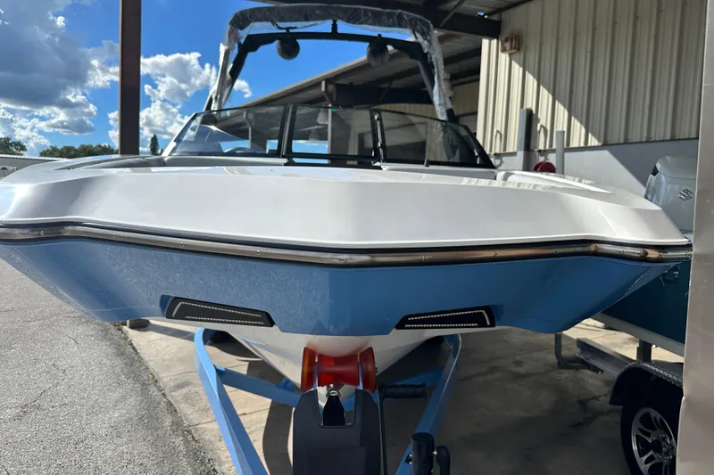 Slide: The Image of 2026 Axis A225 boat in storage, blue and white hull, sunny day. - 13