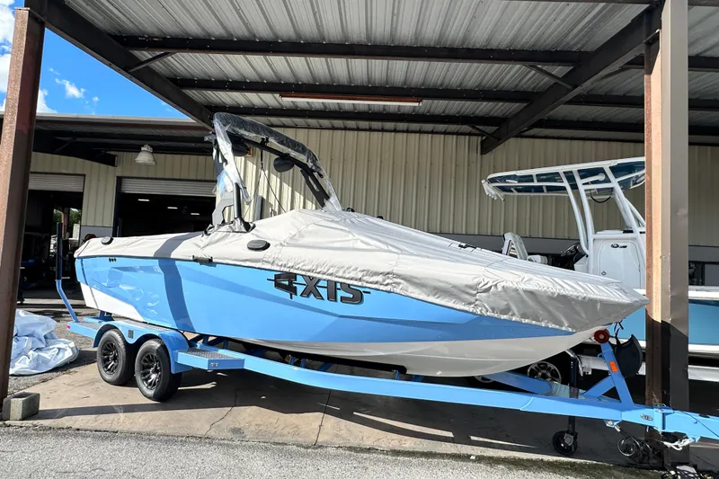 Slide: The Image of 2026 Axis A225 boat with cover on trailer, parked under a metal shelter. - 17