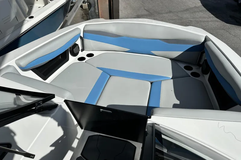 Slide: The Image of 2026 Axis A225 boat interior with blue and gray seating, cup holders, and open windshield. - 3