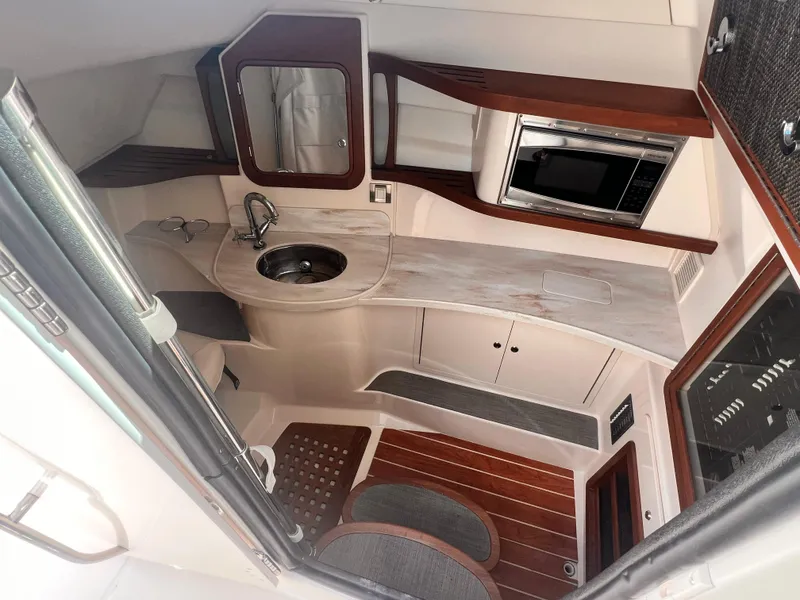 Slide: The Image of 2016 Grady-White Freedom 375 cabin interior with sink, microwave, and wood accents. - 17