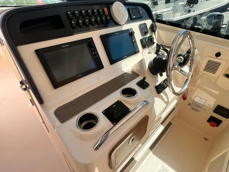 Slide: The Image of 2016 Grady-White Freedom 375 boat dashboard with steering wheel and navigation screens. - 24