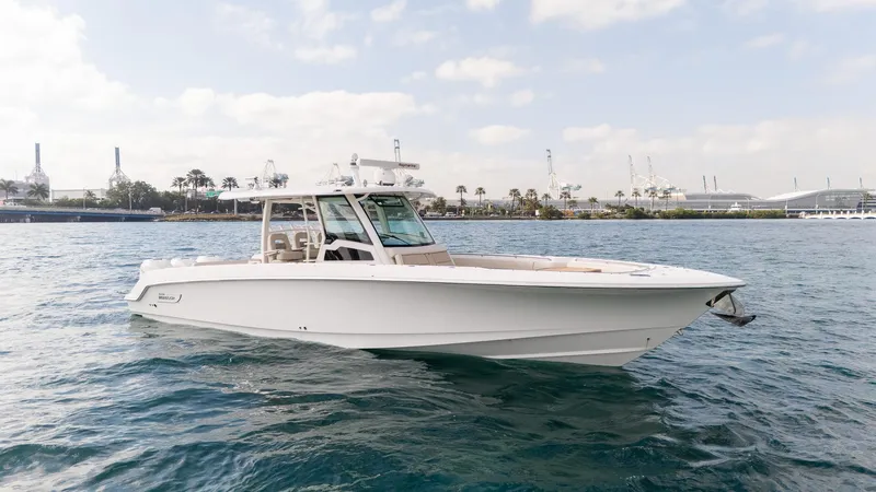 Slide: The Image of 2020 Boston Whaler 380 Outrage boat on water, with industrial background. - 2