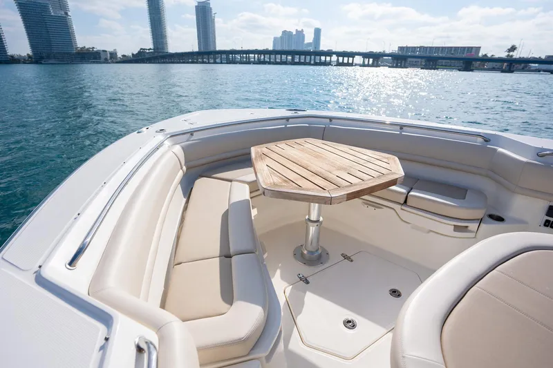 Slide: The Image of 2020 Boston Whaler 380 Outrage boat interior with seating and wooden table, cityscape in background. - 23