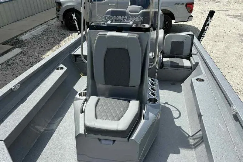 Slide: The Image of 2026 Xpress H22 Bay boat interior with gray seating and console, parked outdoors. - 8