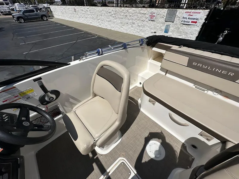Slide: The Image of 2017 Bayliner VR5 Bowrider interior with beige seating and steering wheel in a parking lot. - 20