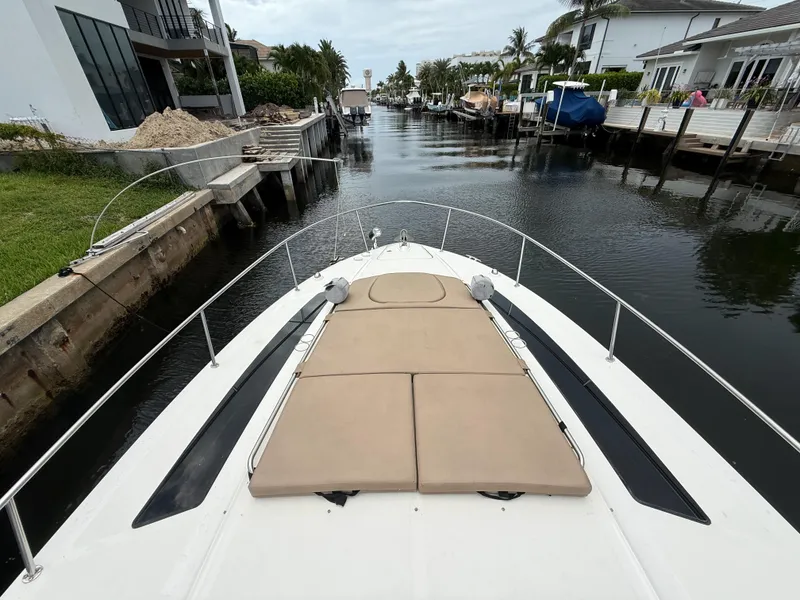 Slide: The Image of 2016 Sea Ray 350 Sundancer cruising in a residential canal, featuring a spacious sunpad. - 15