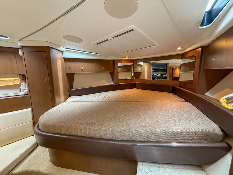 Slide: The Image of 2016 Sea Ray 350 Sundancer cabin interior with luxurious bed and wooden cabinetry. - 21
