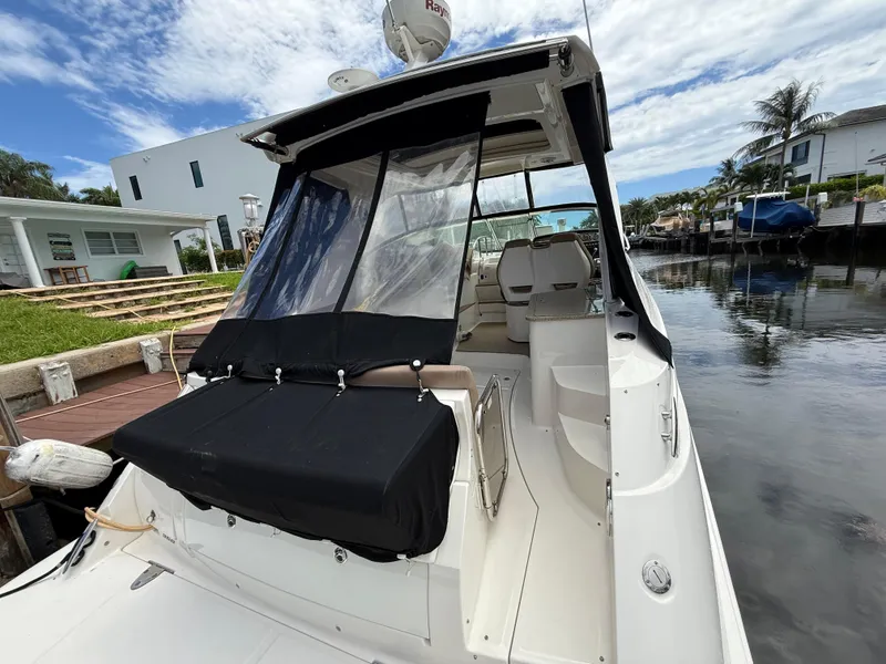Slide: The Image of 2016 Sea Ray 350 Sundancer docked by waterfront homes, featuring covered seating area. - 37