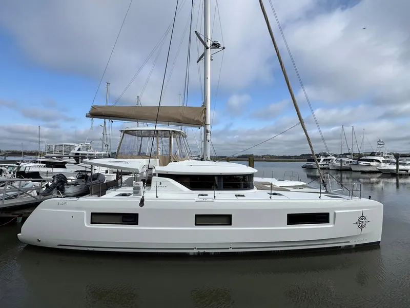 Slide: The Image of 2022 Lagoon 46 catamaran docked at a marina under a cloudy sky. - 1