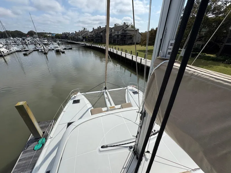 Slide: The Image of 2022 Lagoon 46 catamaran docked in a marina with surrounding boats and waterfront homes. - 17