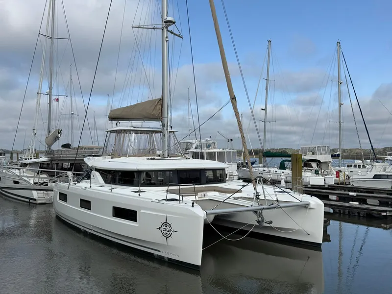 Slide: The Image of 2022 Lagoon 46 catamaran docked at a marina under a cloudy sky. - 2