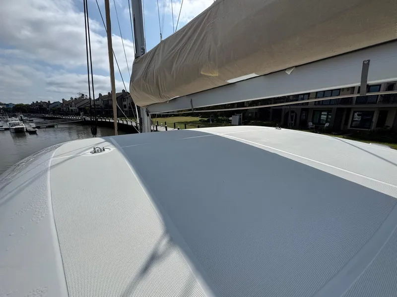 Slide: The Image of 2022 Lagoon 46 catamaran deck with sail, docked at marina under cloudy sky. - 22