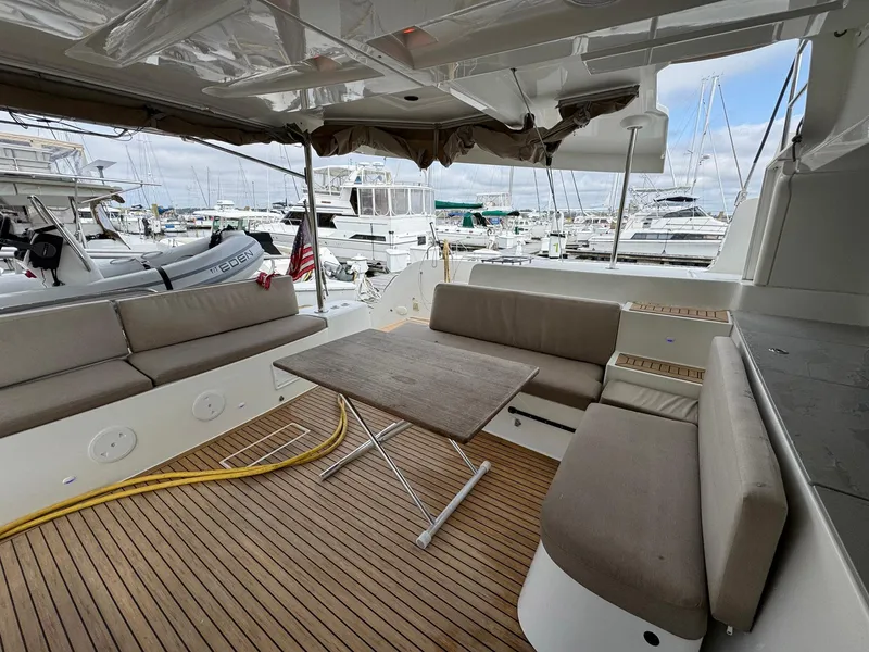 Slide: The Image of Spacious deck of 2022 Lagoon 46 catamaran with seating and table, docked at marina. - 43