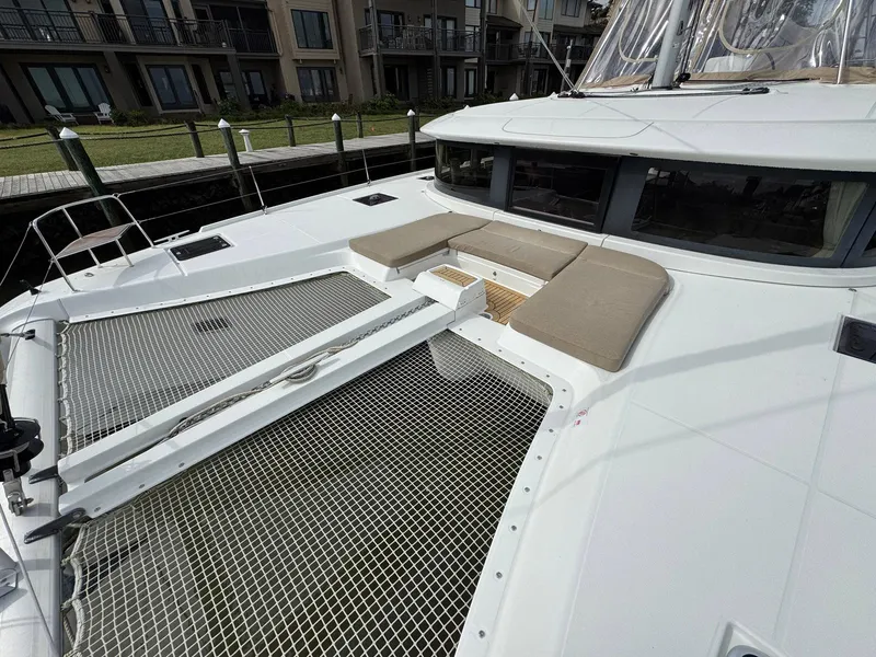Slide: The Image of 2022 Lagoon 46 catamaran with netted deck and cushioned seating area. - 9