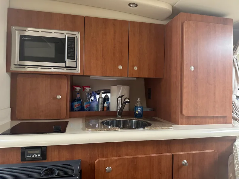 Slide: The Image of 2009 Cruisers 300 CXi Express boat kitchen with microwave, sink, and wooden cabinets. - 6