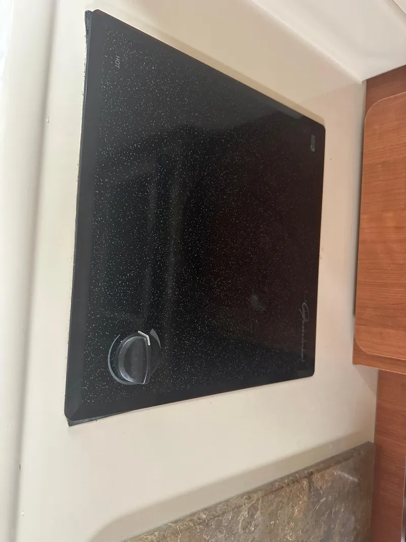 Slide: The Image of 2009 Cruisers 300 CXi Express boat stove with black glass cooktop and control knob. - 10