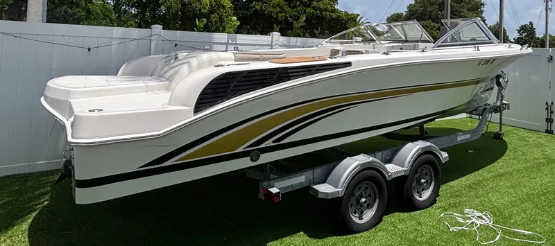 Slide: The Image of Westport 23 Custom Tender 2010 on trailer, white with gold accents, parked on grass. - 2
