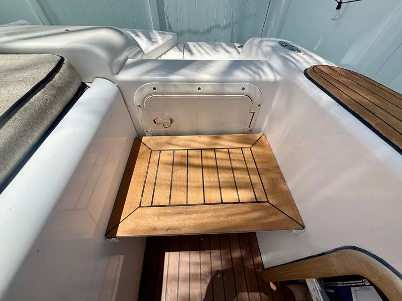 Slide: The Image of Westport 23 Custom Tender 2010, wooden deck detail, white interior, and storage compartment. - 31
