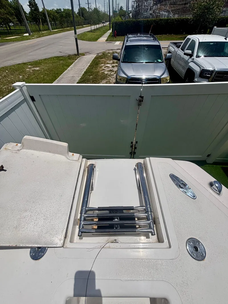 Slide: The Image of 2010 Westport 23 Custom Tender boat with ladder, parked near white fence and vehicles. - 9