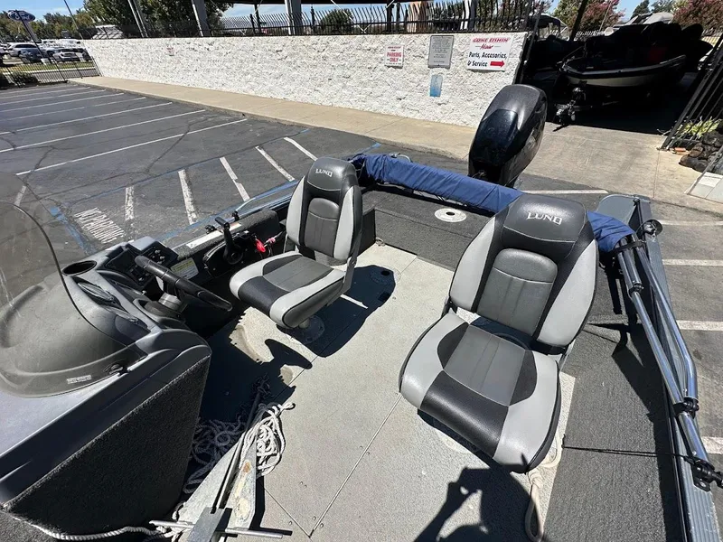 Slide: The Image of 2015 Lund 1625 Fury XL SS boat interior with two seats in a parking lot. - 13