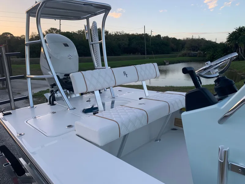 Slide: The Image of 2022 Beavertail Skiffs Vengeance boat interior with seating and steering wheel, near a serene waterway. - 17