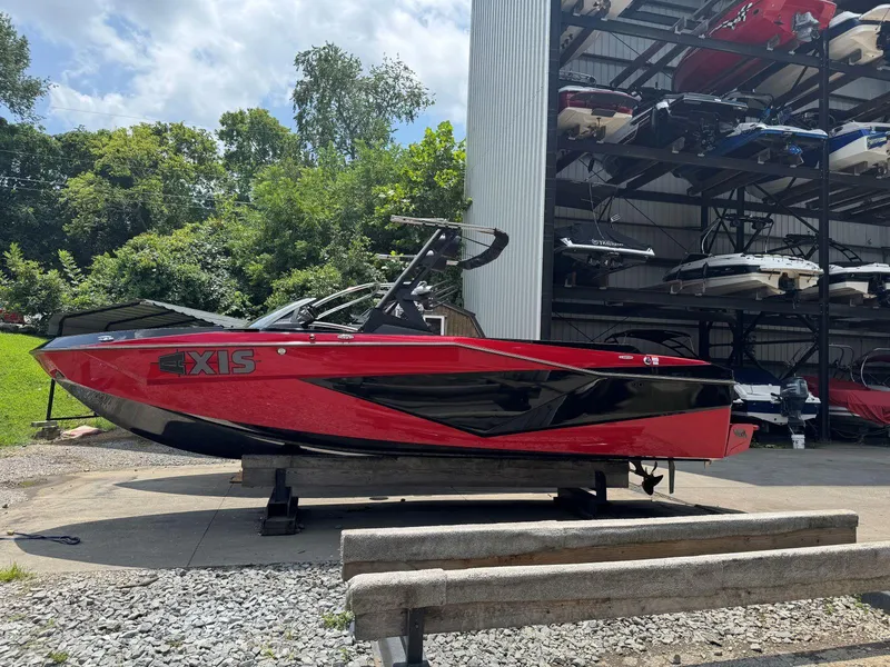 The Image of Red and black 2022 Axis T250 boat on display near storage facility. - 1