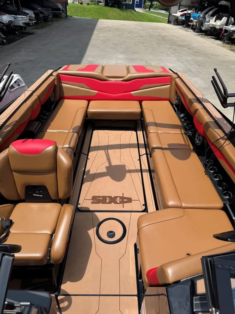 Slide: The Image of 2022 Axis T250 boat interior with tan and red seating, docked outdoors. - 30