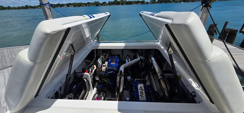 Slide: The Image of 2007 Fountain 42 Executioner boat engine compartment with open hatches, docked by a scenic lake. - 32