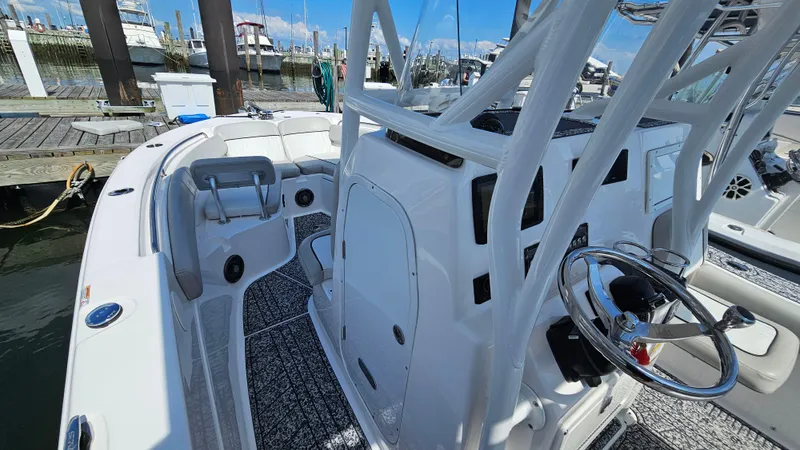 Slide: The Image of 2022 Sea Fox 249 Avenger boat interior with steering wheel and seating at a marina. - 14