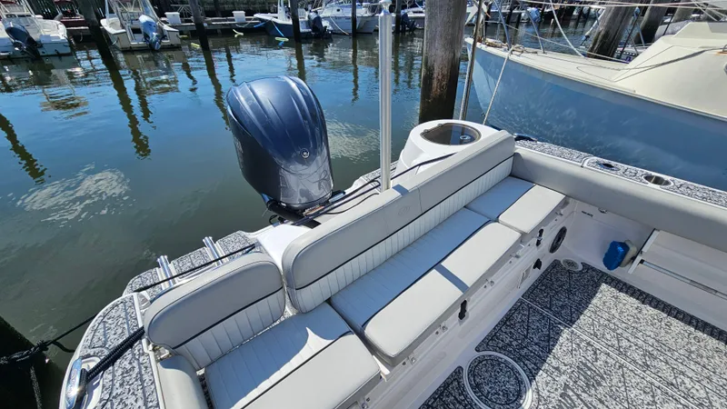 Slide: The Image of 2022 Sea Fox 249 Avenger boat with cushioned seating and outboard motor in a marina. - 8