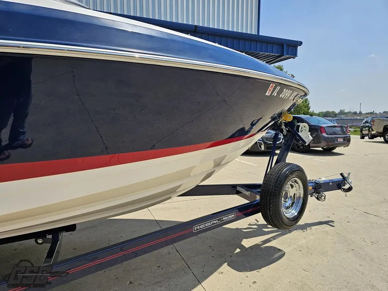 Slide: The Image of 2018 Regal 2300 Bowrider on trailer, parked outdoors near vehicles. - 10